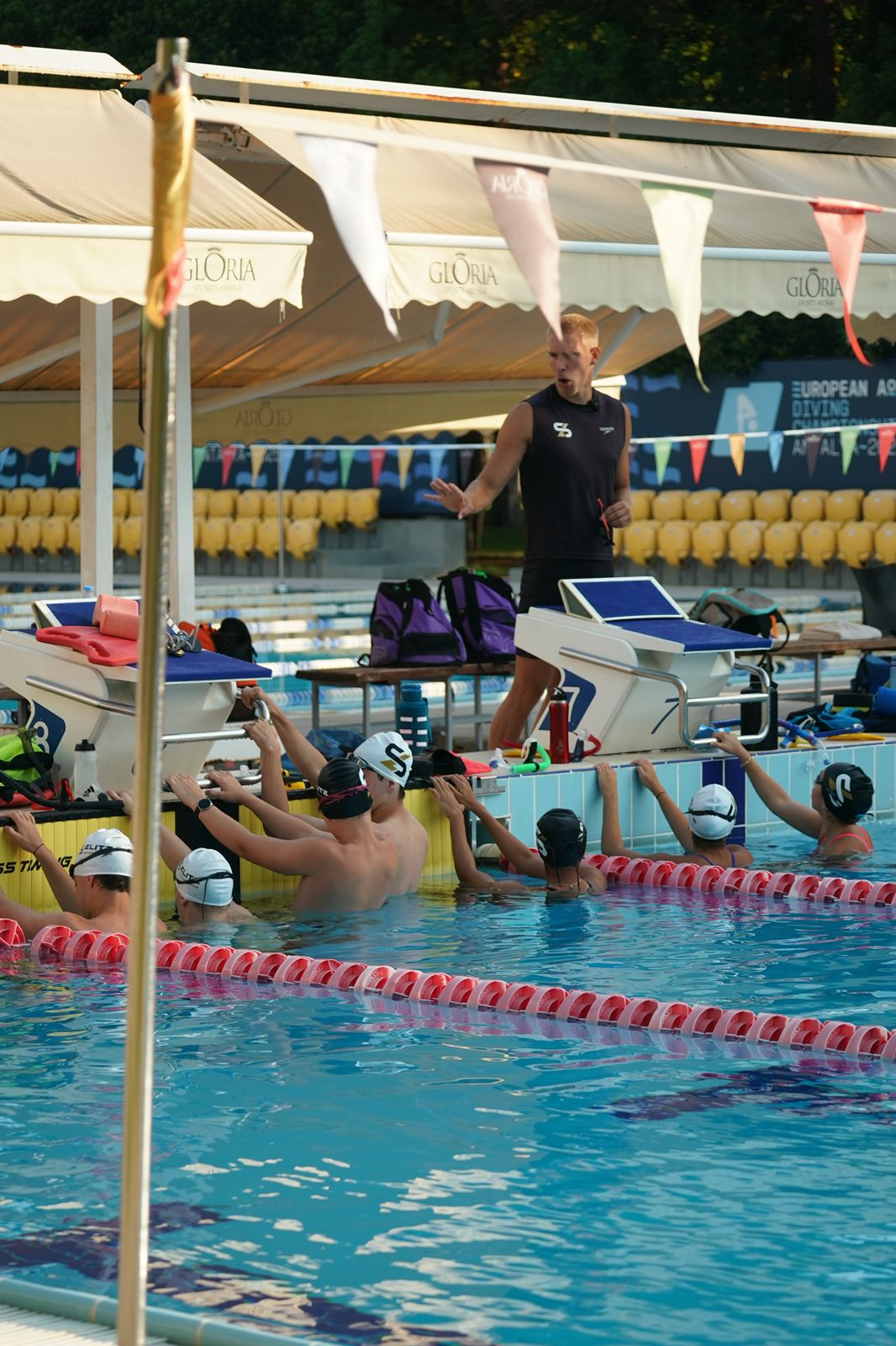 Squad session with swimmers listening at the poolside